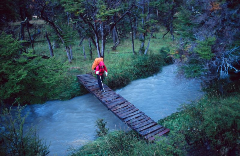 Trekker on foot bridge, Paine Circuit, Torres del Paine NP, Patagonia, Chile.