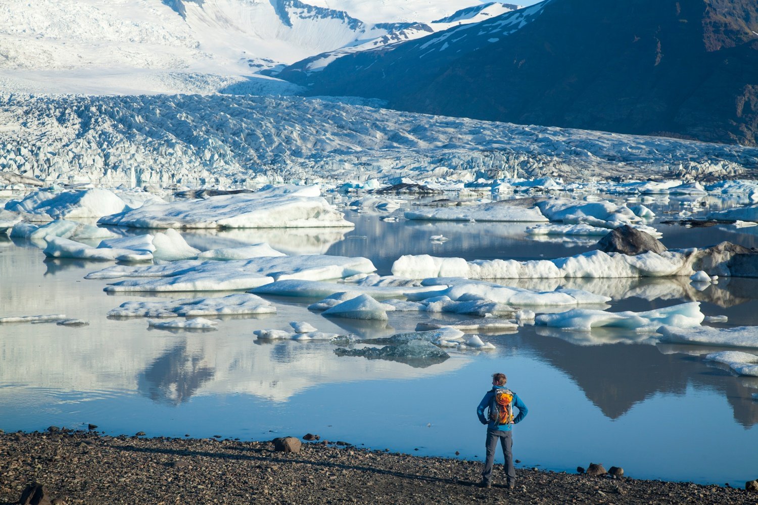 Person beside Fjallsarlon iceberg lagoon, beneath Fjallsjokull glacier, Sudhurland, Iceland. Person beside Fjallsarlon iceberg lagoon, beneath Fjallsjokull glacier, Sudhurland, Iceland.