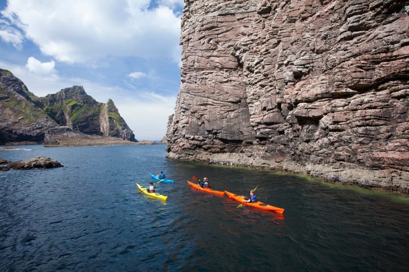 Sea kayakers passing Hag Island, North Mayo seacliffs, Co Mayo, Ireland.